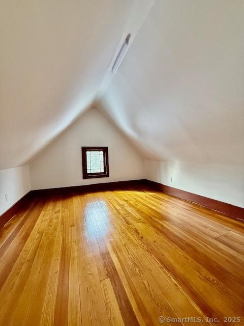 bonus room with lofted ceiling, light wood finished floors, and baseboards