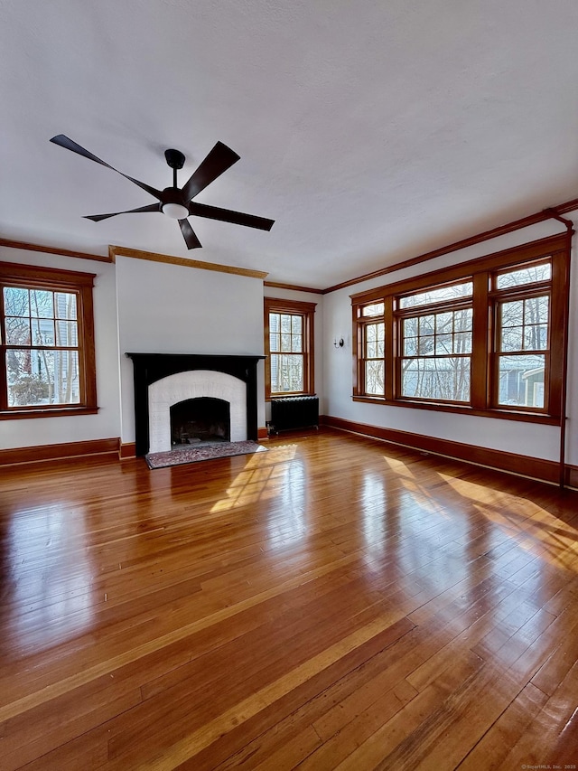 unfurnished living room featuring hardwood / wood-style flooring, baseboards, a fireplace, and ornamental molding