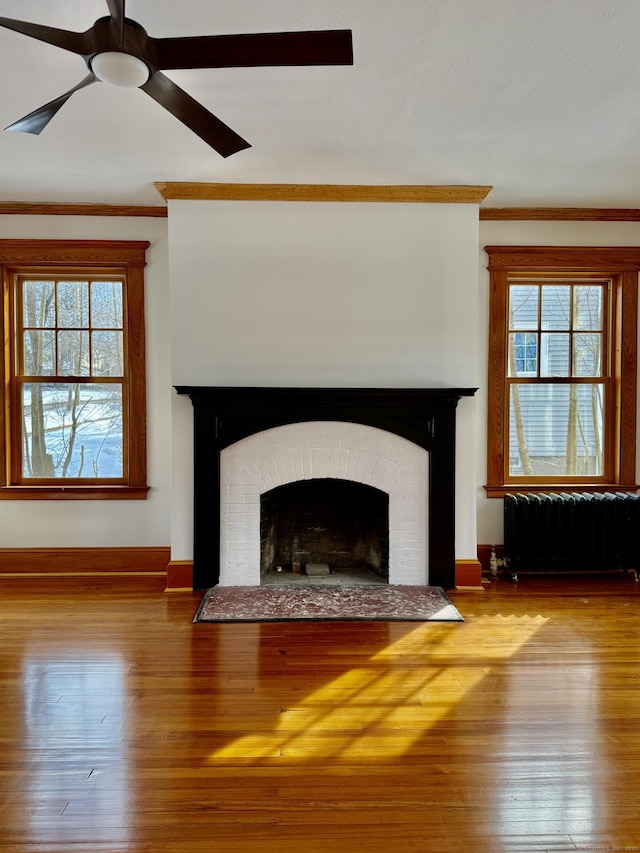 unfurnished living room featuring crown molding, a wealth of natural light, a fireplace, and radiator heating unit