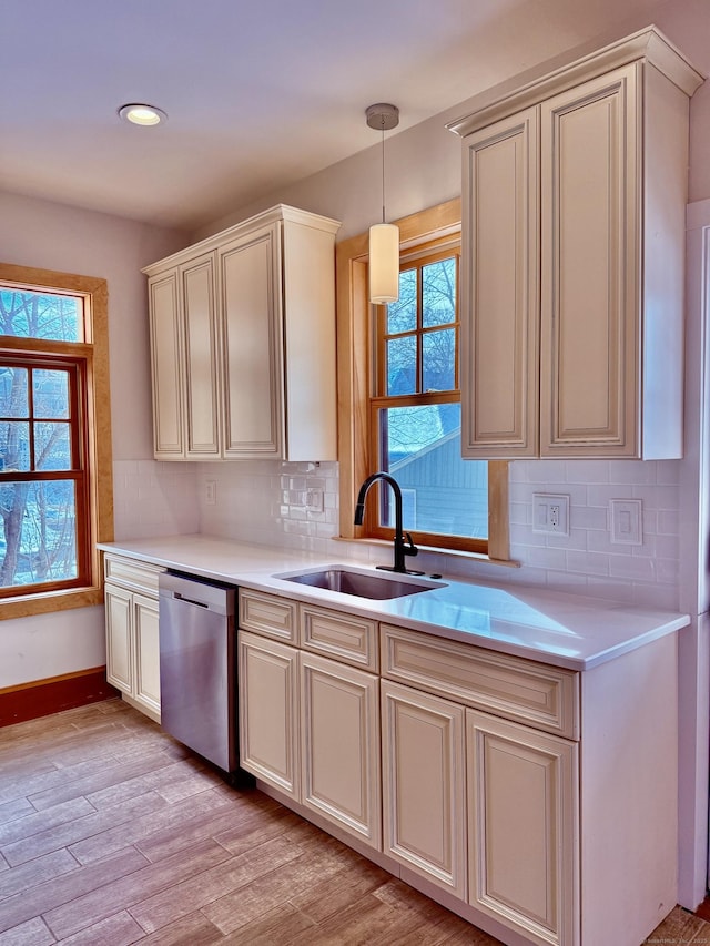 kitchen featuring light wood-type flooring, light countertops, a sink, and stainless steel dishwasher