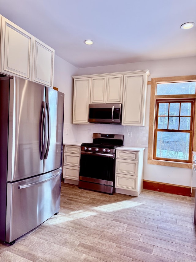 kitchen featuring recessed lighting, stainless steel appliances, baseboards, light countertops, and light wood finished floors