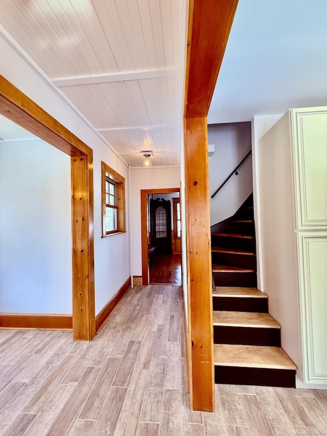 stairway with wooden ceiling, baseboards, and wood finished floors