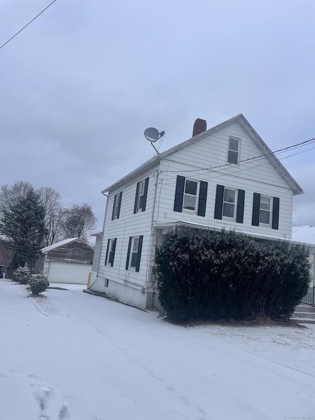 snow covered property with an outbuilding and a chimney