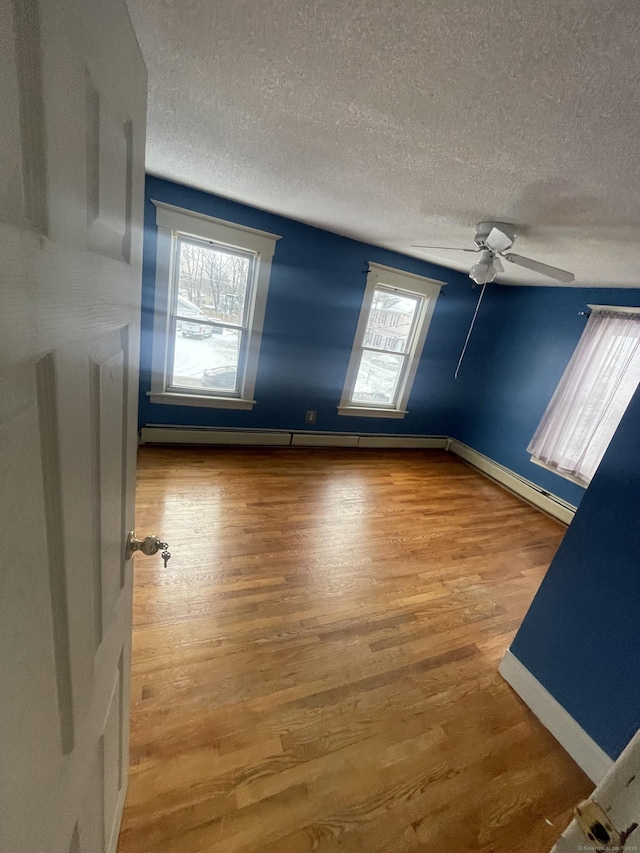 unfurnished room with a ceiling fan, a textured ceiling, baseboards, and wood finished floors