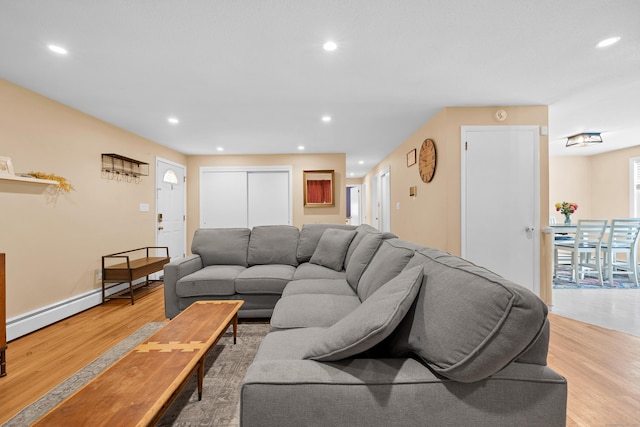 living area with a baseboard heating unit, recessed lighting, baseboards, and light wood finished floors