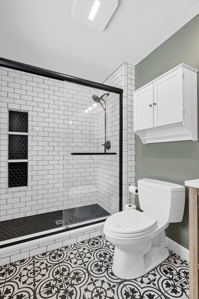 full bath featuring baseboards, a shower stall, toilet, and tile patterned floors