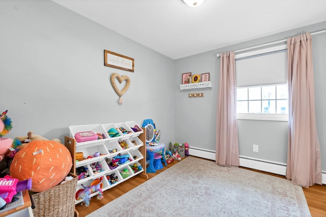 recreation room with a baseboard radiator and wood finished floors