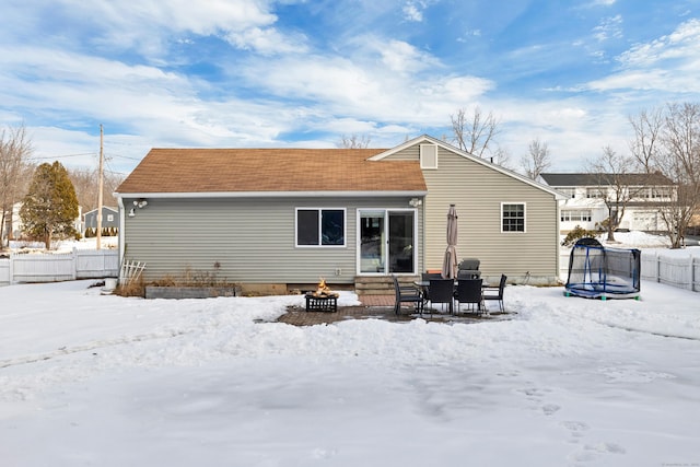 snow covered property featuring a trampoline and an outdoor fire pit