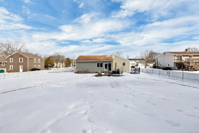 snow covered rear of property featuring a residential view and fence