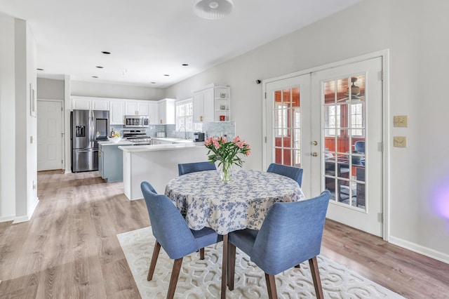 dining area with light wood-style floors, french doors, and baseboards