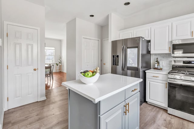 kitchen with stainless steel appliances, light countertops, light wood-style floors, white cabinetry, and backsplash