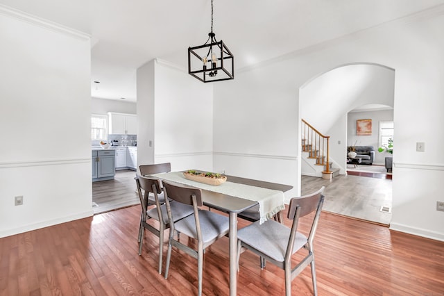 dining area featuring baseboards, stairway, an inviting chandelier, and light wood-style floors