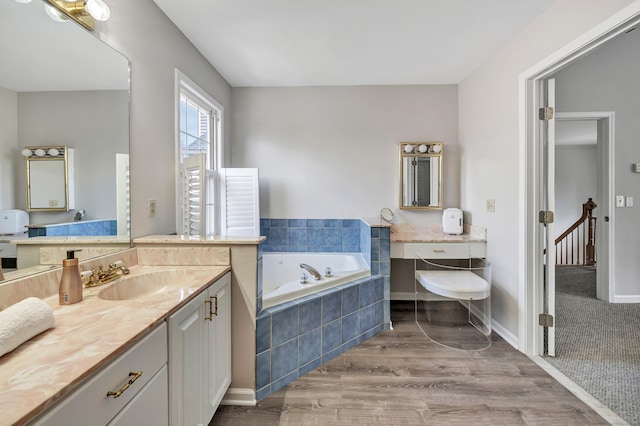 full bathroom featuring a garden tub, baseboards, wood finished floors, and vanity