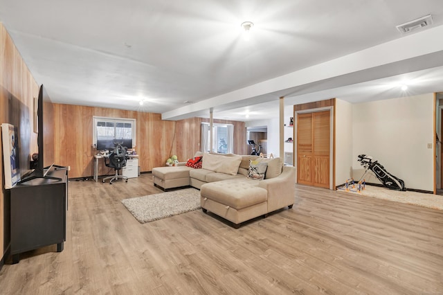 living area featuring wooden walls, visible vents, and light wood-style flooring