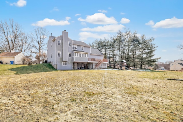 rear view of house with a playground, a chimney, a lawn, stairway, and a wooden deck