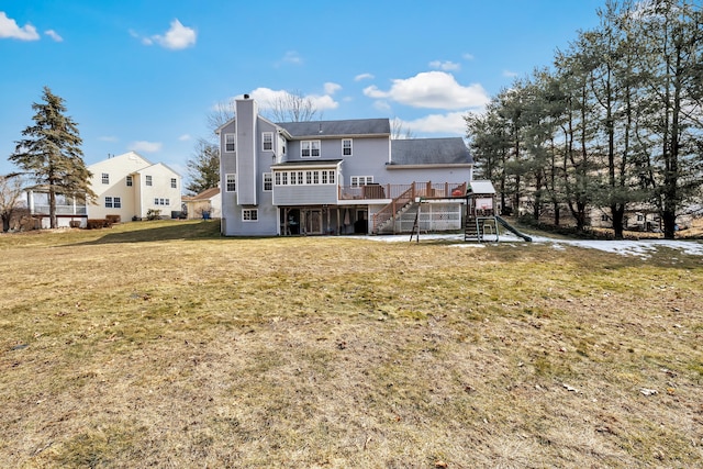 back of property with a yard, a chimney, a playground, and a wooden deck