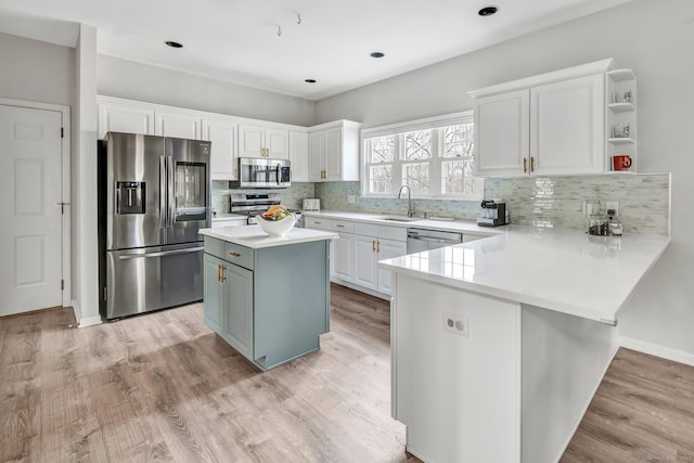 kitchen with light wood-style floors, appliances with stainless steel finishes, white cabinets, and a sink