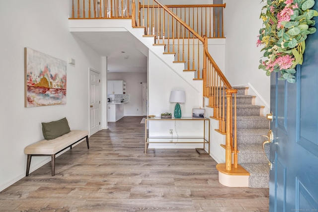 entrance foyer with baseboards, stairway, a towering ceiling, and wood finished floors