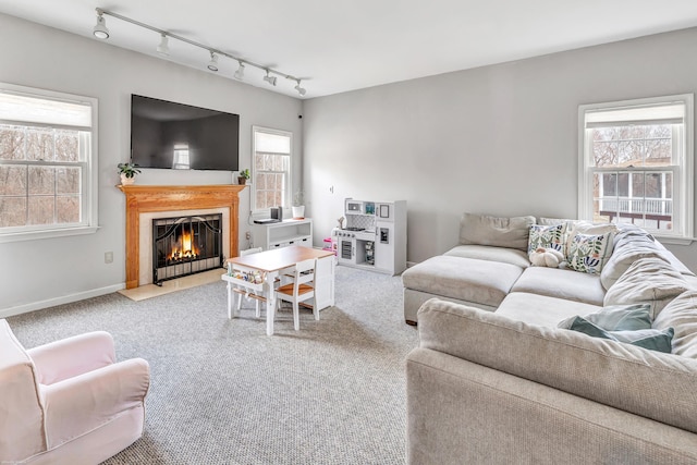 carpeted living area featuring a fireplace with flush hearth, track lighting, and baseboards