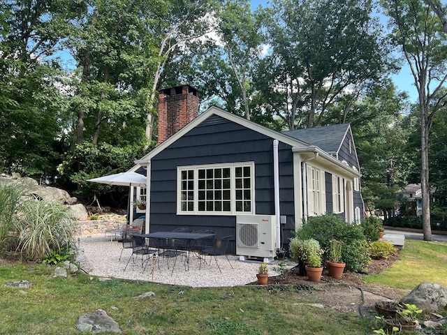 exterior space featuring a patio area, a shingled roof, a chimney, and ac unit