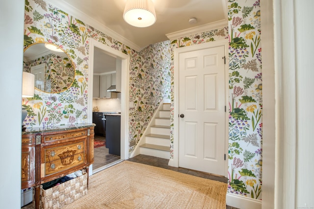 foyer entrance with ornamental molding, stairs, and wallpapered walls