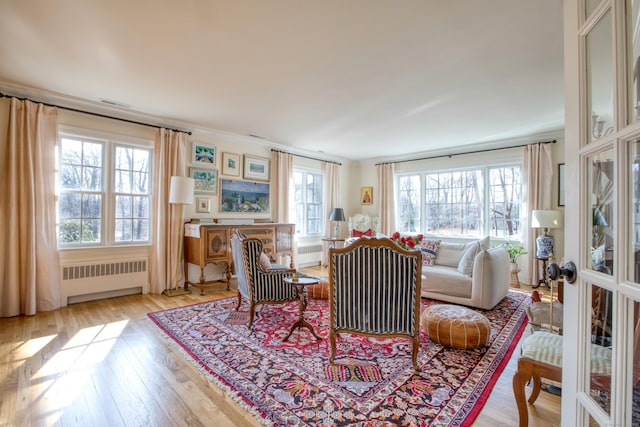 living area featuring light wood-style floors, radiator, and a healthy amount of sunlight