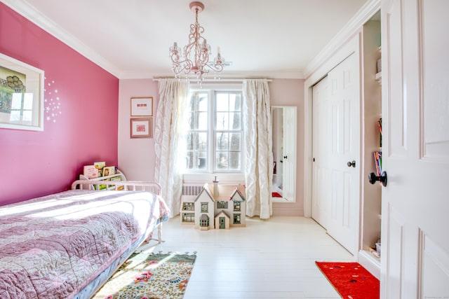 bedroom featuring a closet, a chandelier, crown molding, and wood finished floors