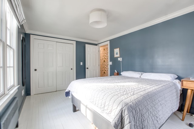 bedroom featuring light wood-style floors, a closet, crown molding, and radiator heating unit