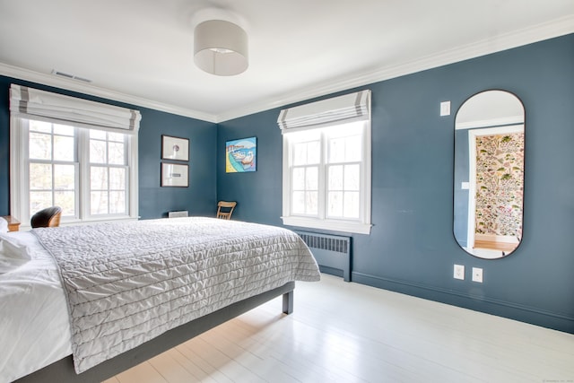 bedroom with crown molding, radiator, visible vents, wood finished floors, and baseboards