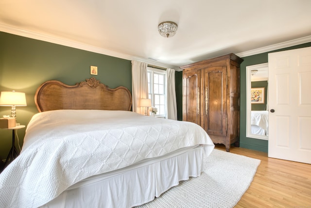 bedroom with light wood-style floors, visible vents, and crown molding