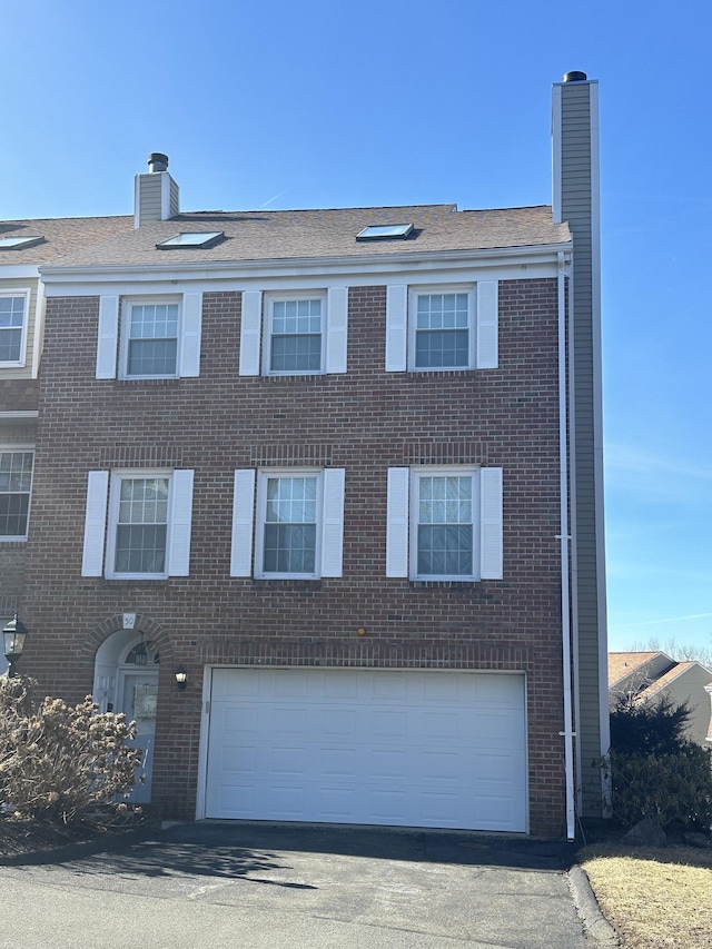 view of front of home featuring aphalt driveway, brick siding, and a chimney