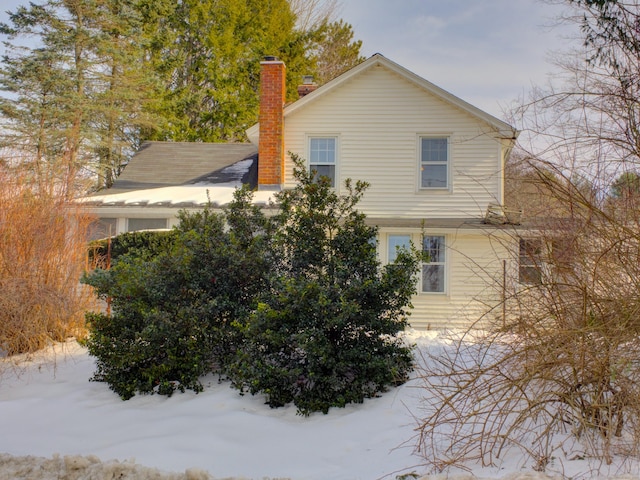 view of snow covered exterior with a chimney