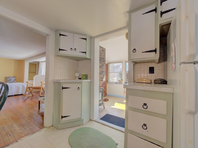 kitchen featuring white cabinets, light countertops, decorative backsplash, and freestanding refrigerator