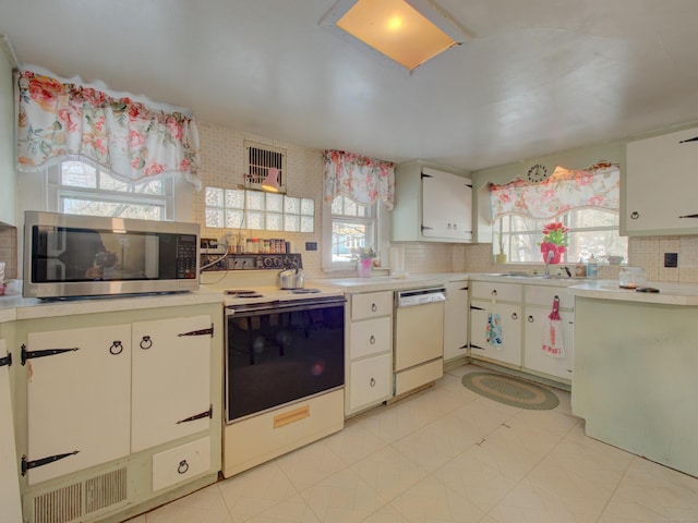 kitchen featuring visible vents, light countertops, backsplash, white cabinets, and white appliances