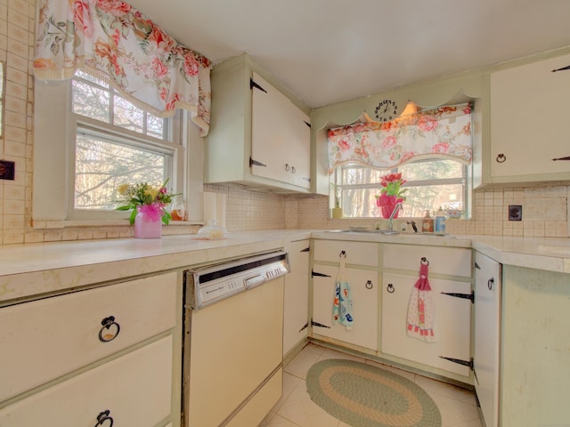 kitchen with white cabinets, light countertops, white dishwasher, and backsplash