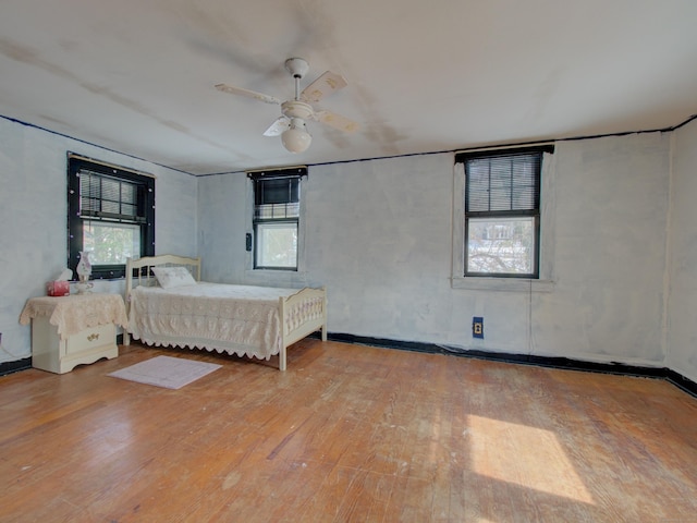 bedroom with light wood-style flooring, multiple windows, and ceiling fan