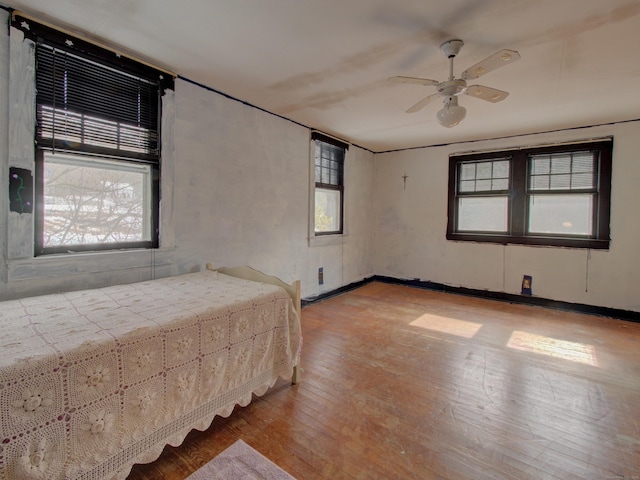 unfurnished bedroom with ceiling fan, light wood-type flooring, and baseboards