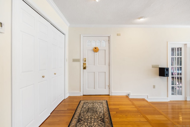 entrance foyer with baseboards, a textured ceiling, ornamental molding, and wood finished floors