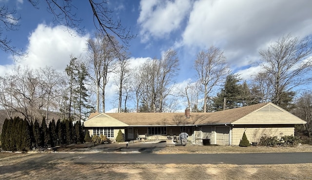 single story home featuring driveway and a chimney