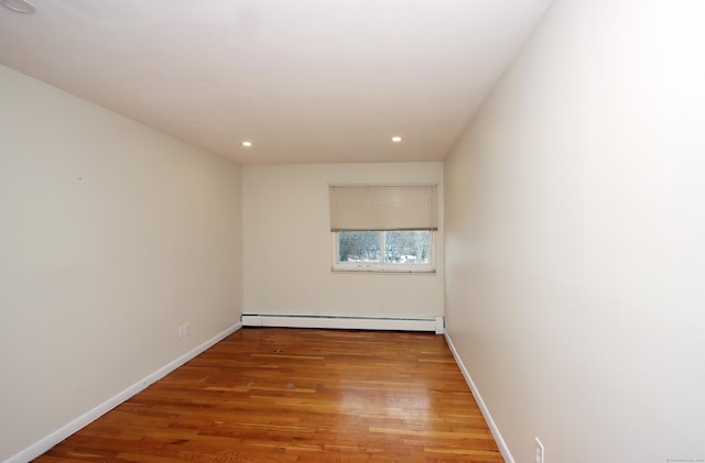 spare room featuring a baseboard radiator, recessed lighting, baseboards, and wood finished floors