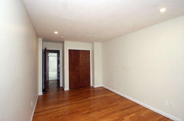 unfurnished bedroom with recessed lighting, a closet, dark wood finished floors, and baseboards