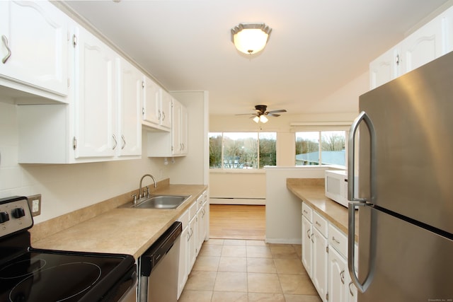 kitchen with a sink, stainless steel appliances, light countertops, and white cabinetry