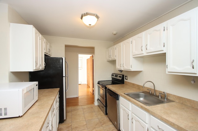 kitchen featuring stainless steel appliances, light countertops, decorative backsplash, white cabinets, and a sink