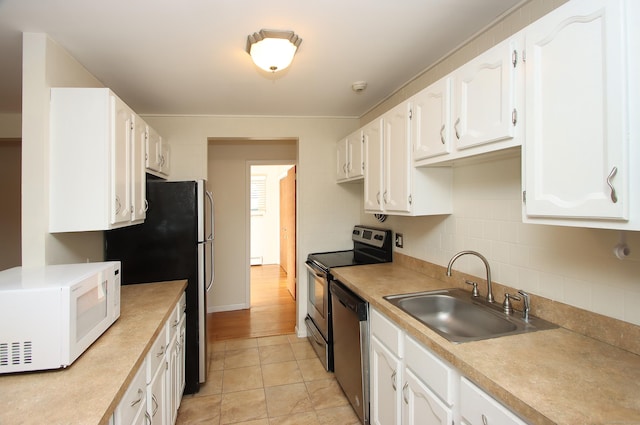 kitchen featuring tasteful backsplash, stainless steel appliances, light countertops, white cabinetry, and a sink