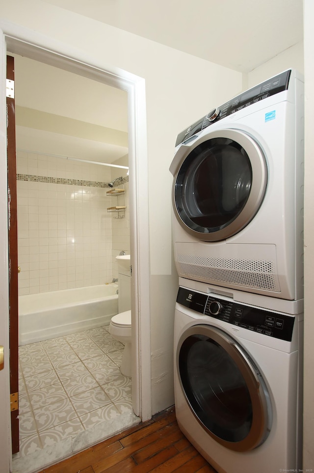 laundry area featuring stacked washing maching and dryer, laundry area, and wood finished floors