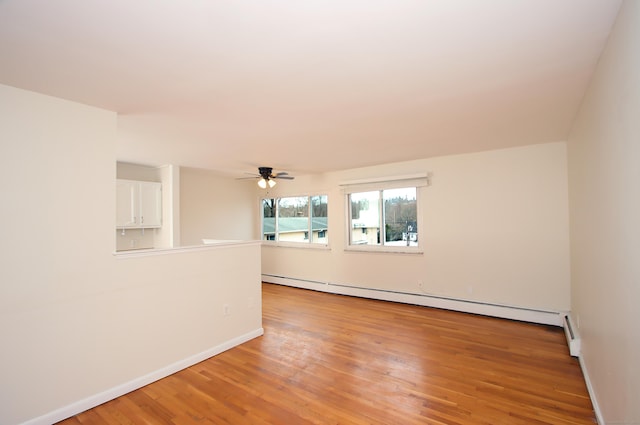 spare room with baseboards, ceiling fan, light wood-style flooring, and baseboard heating