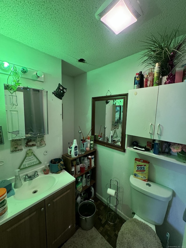 bathroom with toilet, a textured ceiling, and vanity