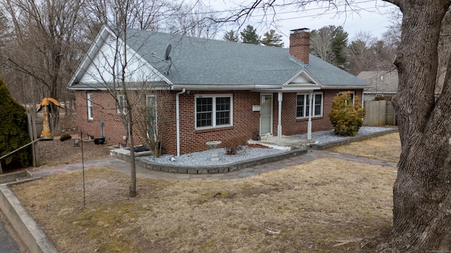 view of front of property featuring a shingled roof, brick siding, fence, and a chimney