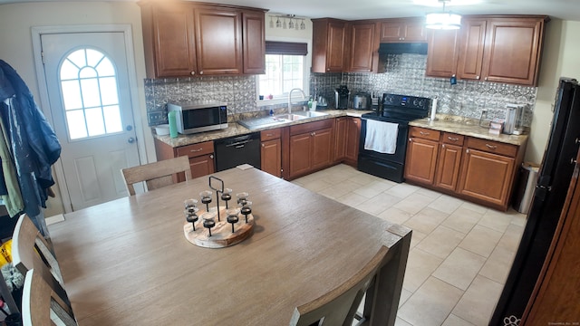 kitchen with decorative backsplash, brown cabinetry, a sink, under cabinet range hood, and black appliances