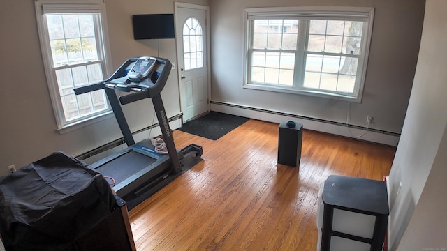 exercise room with baseboard heating and wood-type flooring